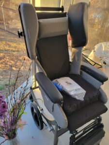 wheelchair with cushioned seat, arm rests, cushioned leg supports, and a head rest, with additional cushions on the left and right of the head rest