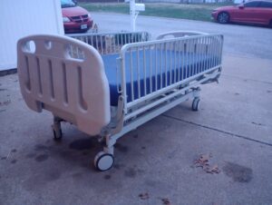 angled side view of hospital bed with rails on all sides and wheels