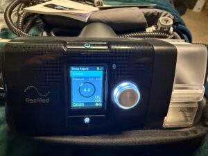 Front view of black CPAP machine. The machine has a digital screen that displays the sleep report, pressure, and additional information.