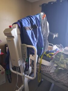 White lift attached to bed. 2 mesh slings, one blue and one gray, hang over the lift. Next to new condition.