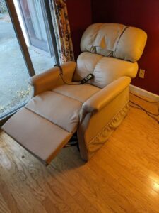 Tan recliner extended out, with a remote control attached