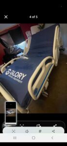 Three-quarter view of hospital bed. Mattress has logo that says “Glory Medical Equipment.”
