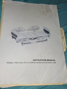 Instruction manual for hospital bed. Manual lists the bed as a multifunctional electric bed. Manual also lists the bed as MODEL: PAM-5 and as Item Number LS-EA5003. Manual is slightly wrinkled and stained.