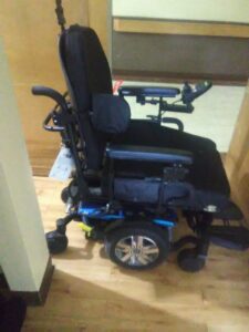 A side view of a power wheelchair with a blue base.