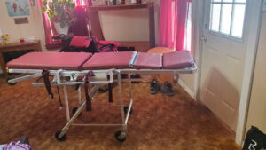 side view of a stretcher laying flat, with wheels and a short bar on each side