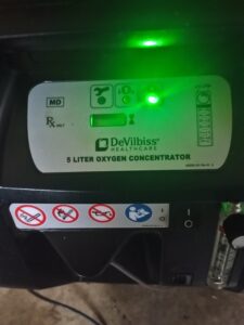 black machine with on/off button on the front and several warning signs including no smoking and no flames,. Top of the device reads