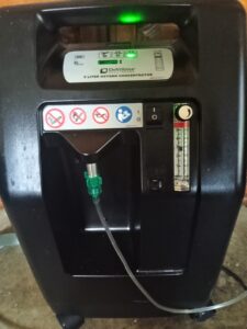 picture shows front on black machine, roughly the size/shape of a suitcase. Device shows several warning signs on the front like no smoking, has an on/off button, has some kind of level indicator, and there is a small hose attached to the machine