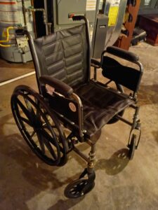 manual wheelchair with arm rests, small wheels in the front, large wheels in the back, and handles to push the wheelchair