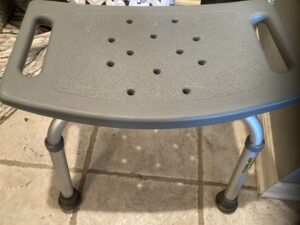 gray rectangular seat with handles, several small holes and 4 short legs