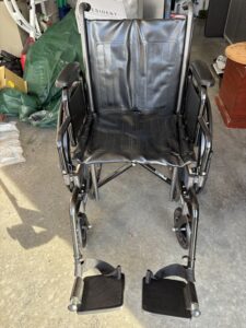 black, manual wheelchair with arm rests, foot rests, and handles on the back to push