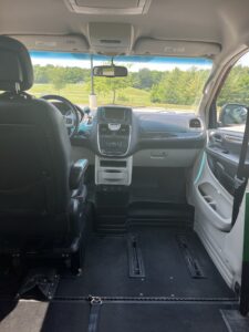 view of accessible van from the inside. Van shows driver's side with regular seat, and passenger side with no seat, and a place to lock in a wheelchair
