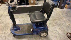 side view of a black and blue power scooter with a seat, a foot platform, and steering handles connected to a pivotable post