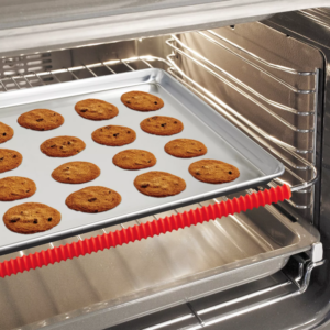 A red, tube-shaped oven rack guard is snapped onto the front rail of an oven rack.