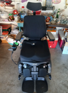 Black power chair with molded Jay Fusion seat cushion and separated footrests. Texture of headrest, backrest, and seat covers appear to have a soft fabric-like texture as opposed to a leather texture. Permobil logo is visible. Like new to gently used condition.