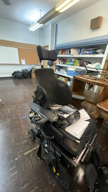 Front view of power chair. An assortment of items are on the seat.
