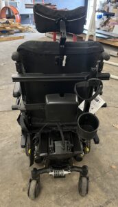 Back view of power wheelchair. A power pack and a cup holder are attached to the back of the chair.