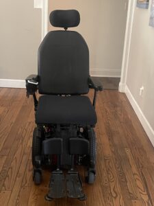 front view of a power wheelchair with a headrest, arm rests, and foot holders