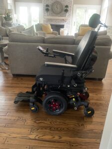 side view of a power wheelchair with a headrest, arm rests, and foot holders
