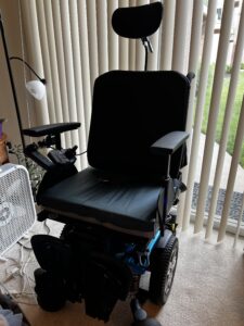 front view of an electric wheelchair with arm rests, a footrest, and a headrest