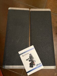 2 rectangular ramp pieces with sandpaper like material and a Titan Electric Wheelchair owner's manual