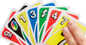 Person holding a variety of Uno cards in several different colors, with a variety of numbers and symbols, feeling the braille on one of the cards