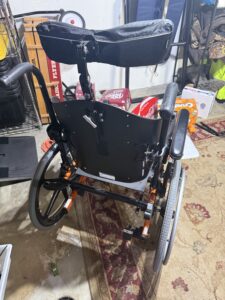 Back of wheelchair, showing push handles and padded headrest.