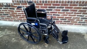 side view of a manual wheelchair with handles to push, arm rests, and foot rests